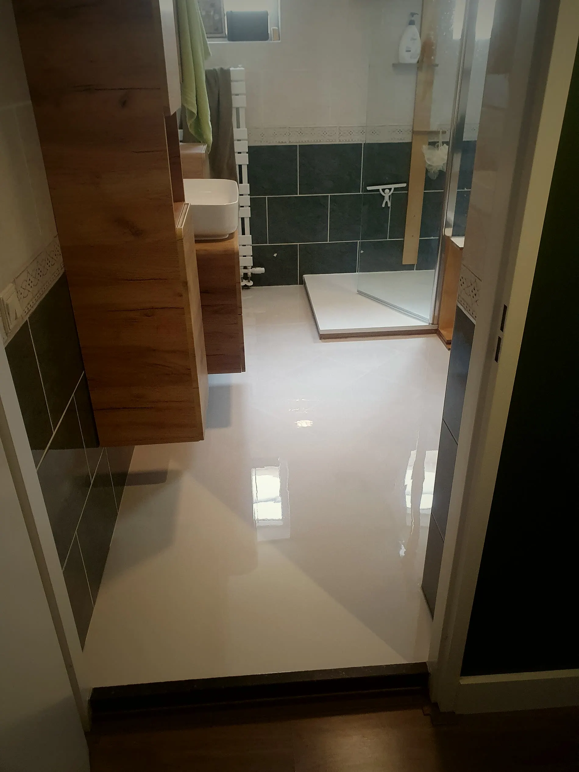 Badkamer met een witte hoogglans gietvloer, houten wastafelmeubel en inloopdouche
