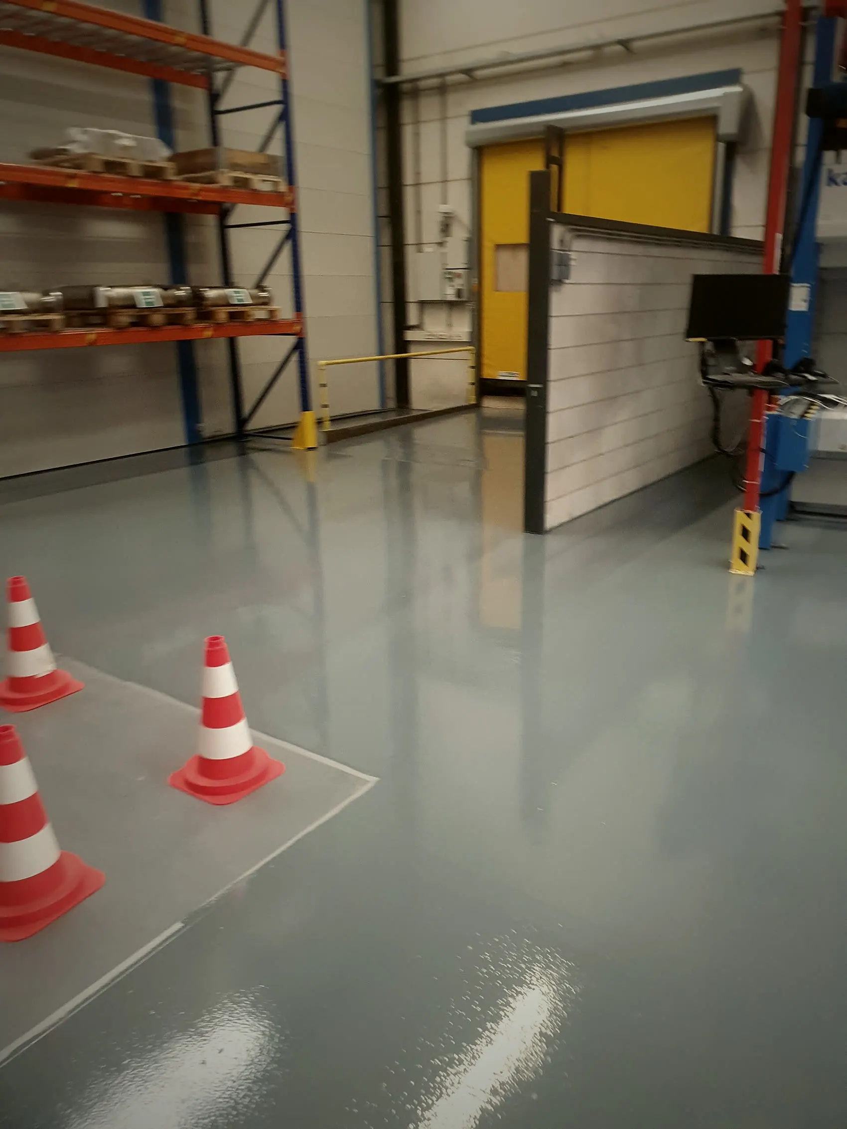Magazijn met epoxyvloer, stellingen en afzetkegels