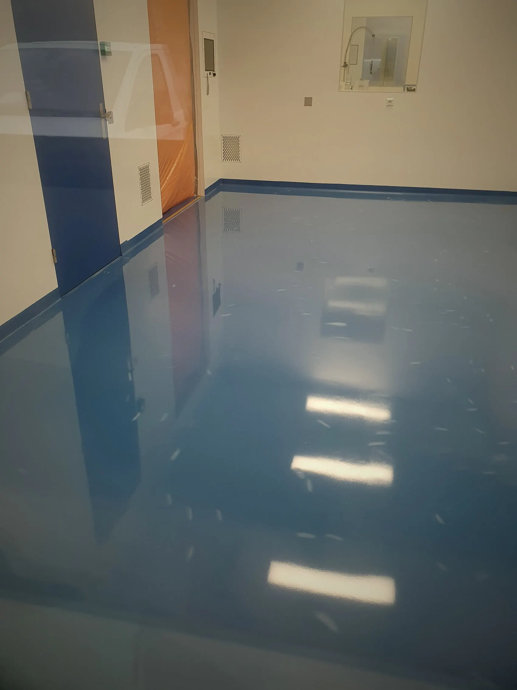 Werkruimte met blauwe epoxyvloer waarin de verlichting doorloopt