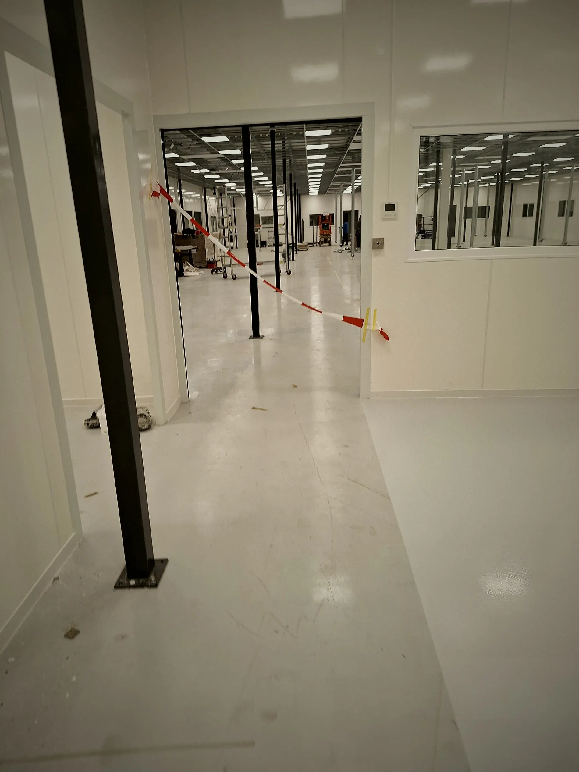 Kantoorgang met witte gietvloer en zwarte stalen kolommen