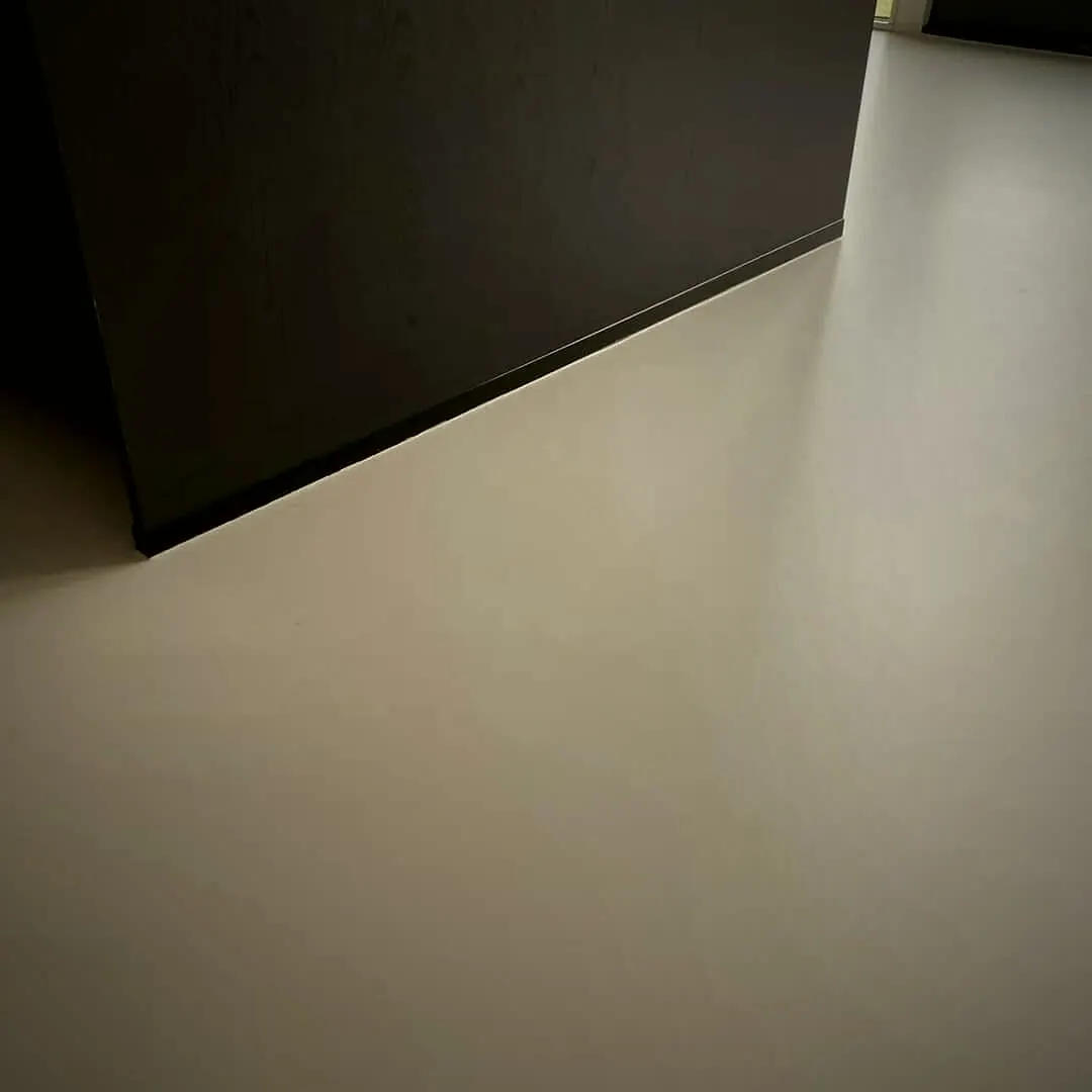 Keuken met zwarte kasten en een lichte naadloze gietvloer