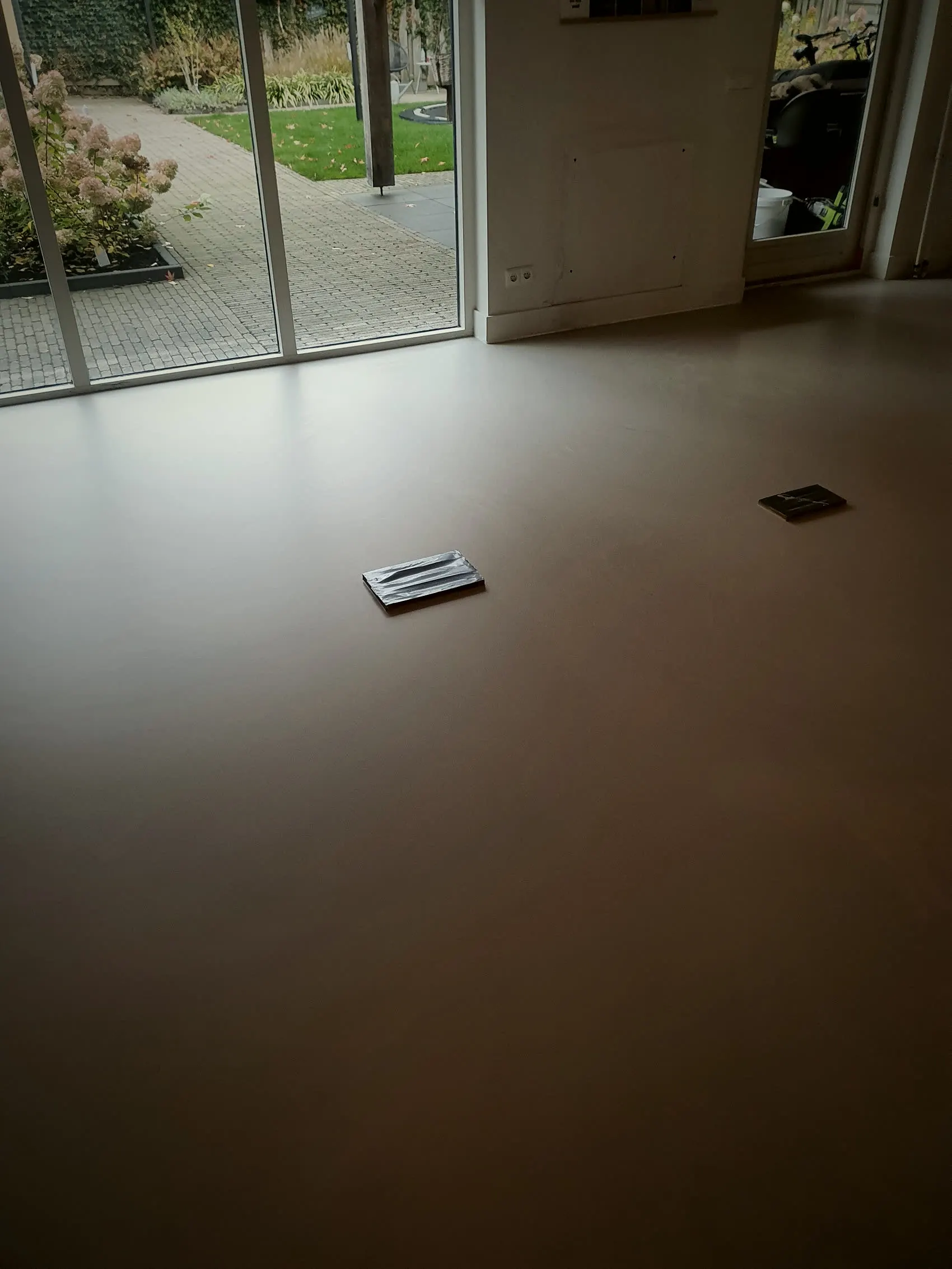 Woonkamer met gietvloer die doorloopt tot aan de tuindeuren