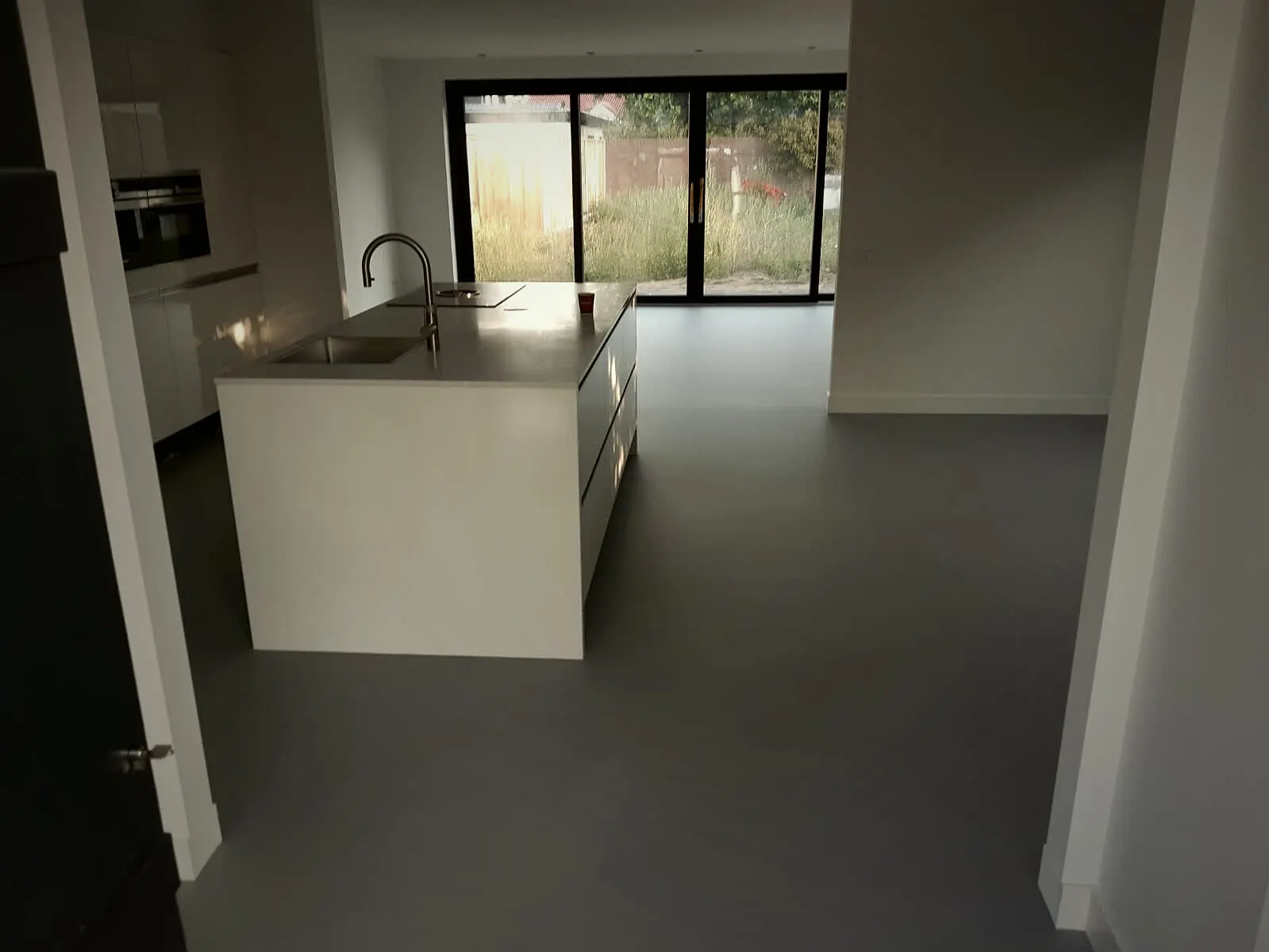Keuken met kookeiland en een doorlopende, afgewerkte grijze gietvloer