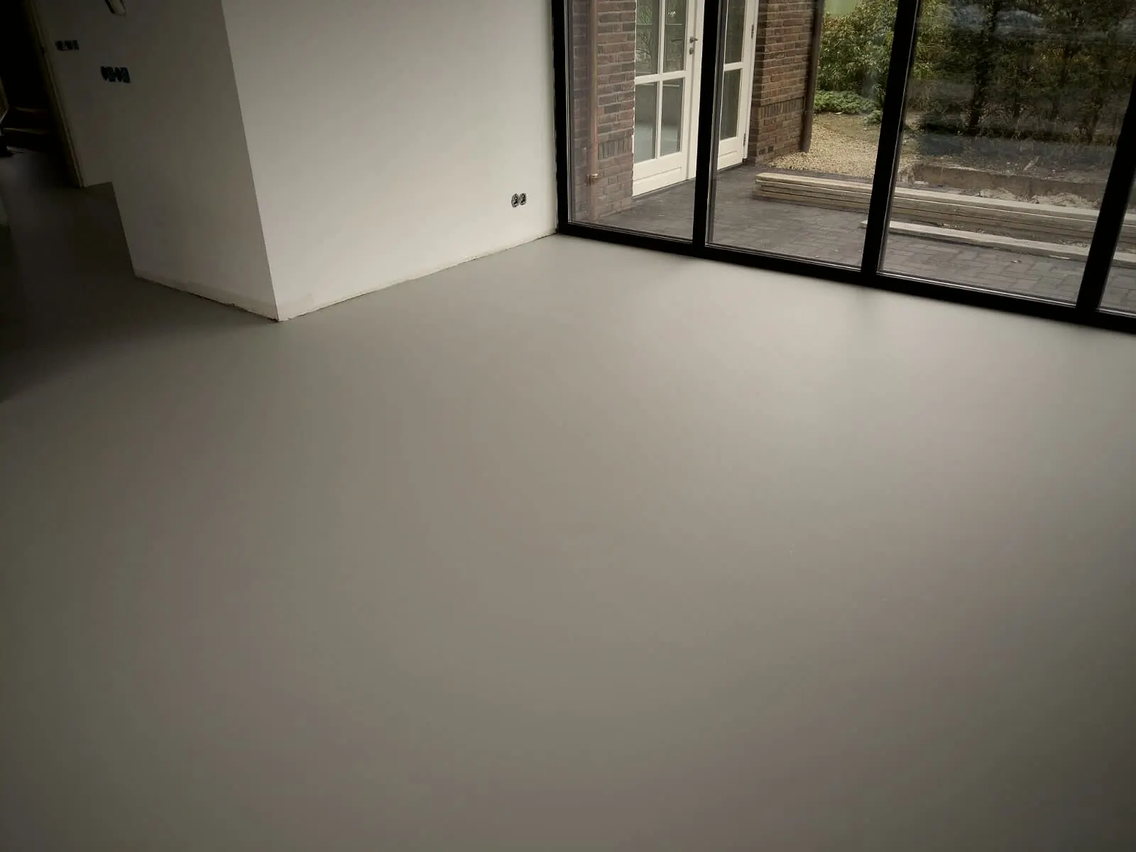 Ruime woonkamer met zwarte kozijnen en lichte gietvloer
