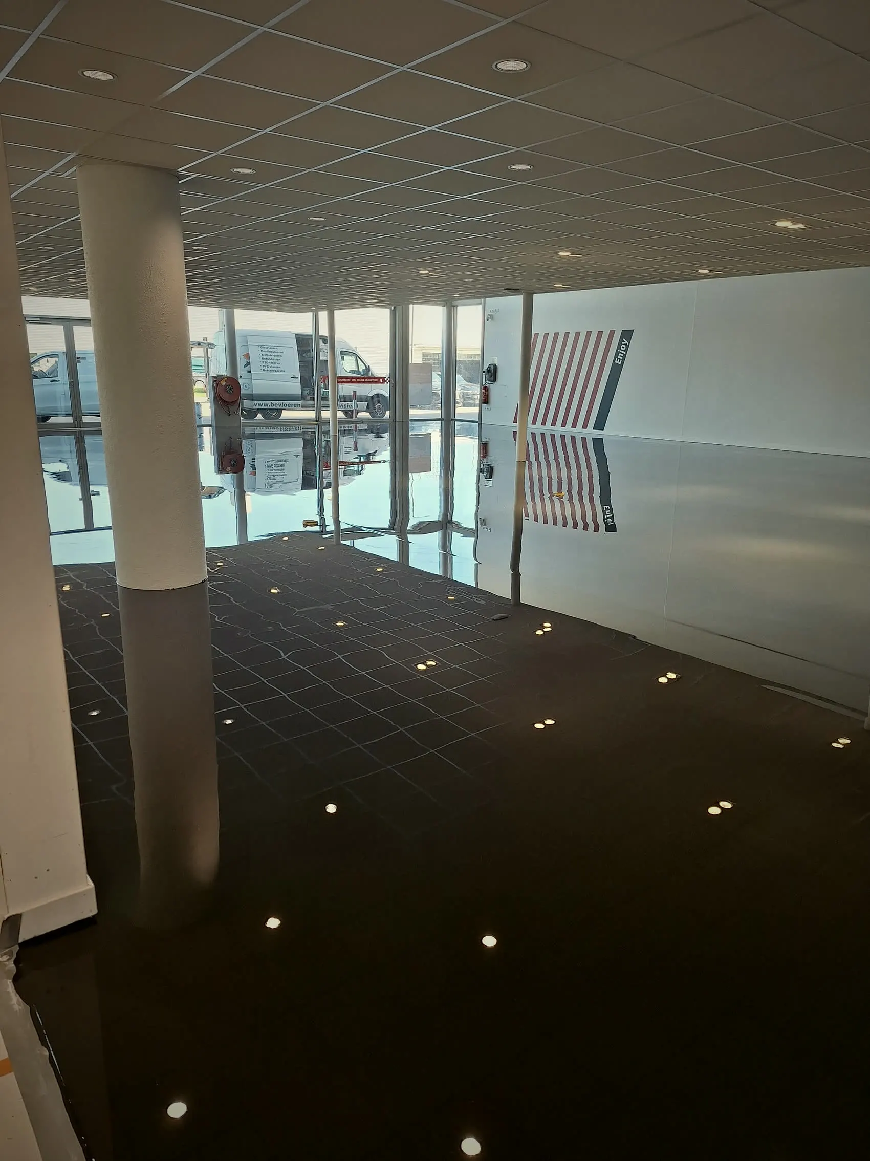 Showroom met donkere naadloze PU gietvloer die de inbouwspots weerspiegelt