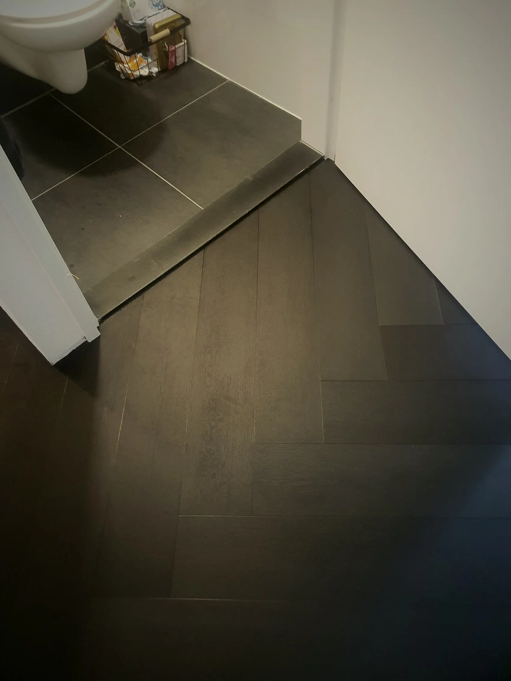 Gang met donkere houtlook PVC vloer, met de drempel naar het toilet