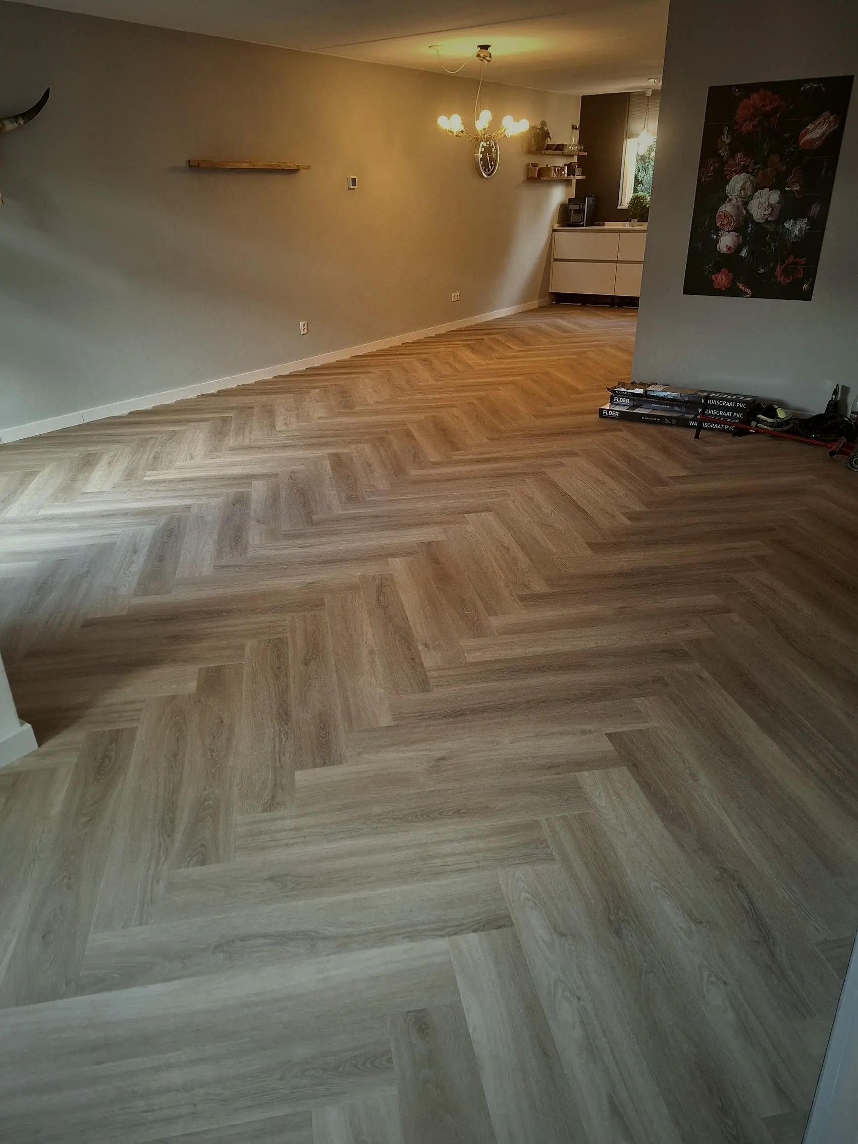 Woonkamer met afgewerkte visgraat PVC vloer onder een schuine kap